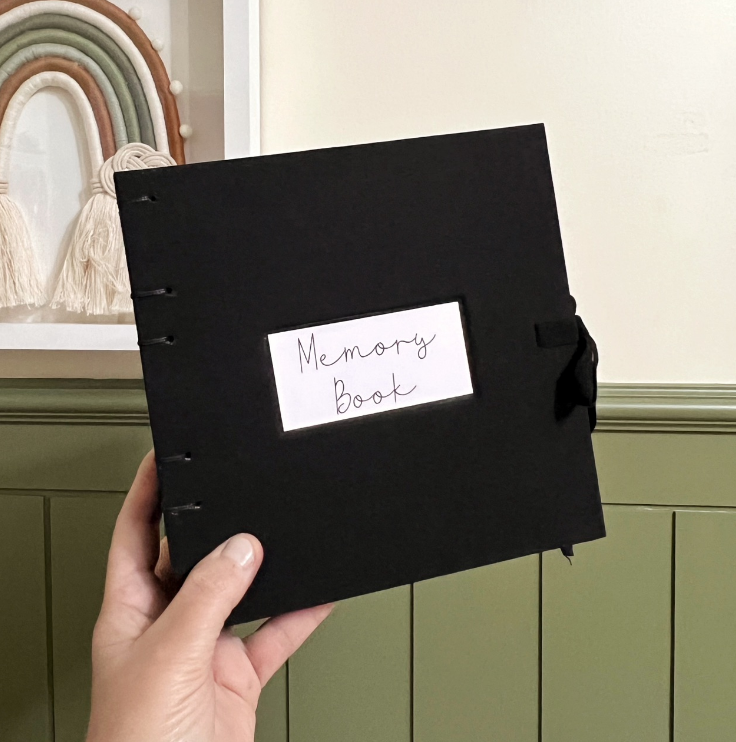 Álbum preto de memórias com etiqueta manuscrita e fechamento em fita